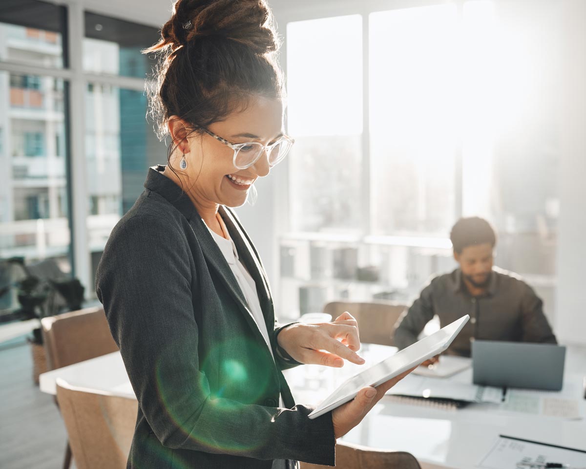 woman in office smiling while using computer tablet