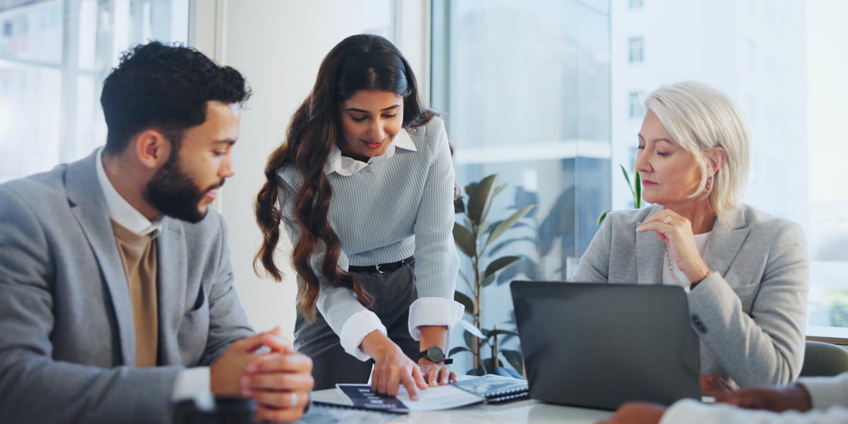 three colleagues reviewing paper at conference table