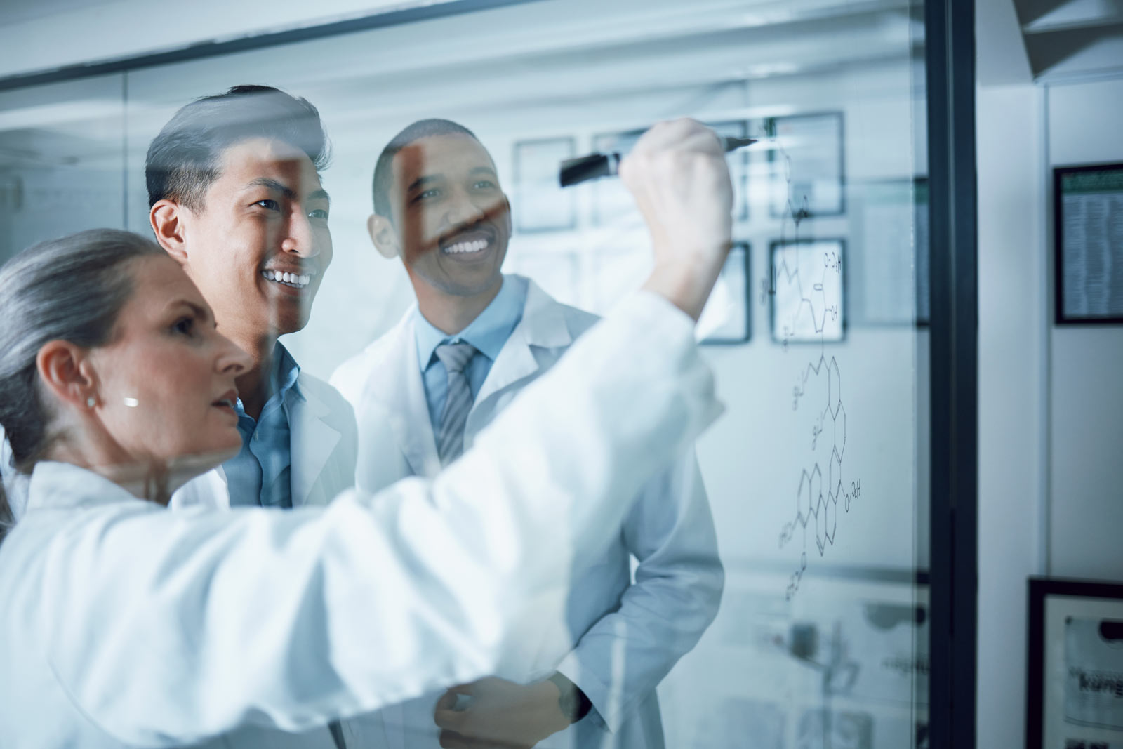 three scientists reviewing glass board