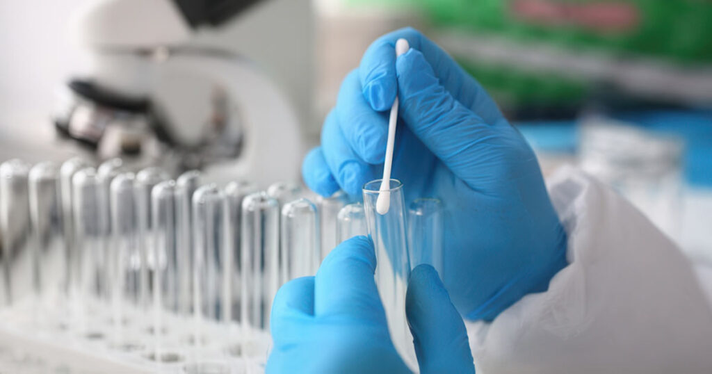scientist wearing gloves swabbing vial