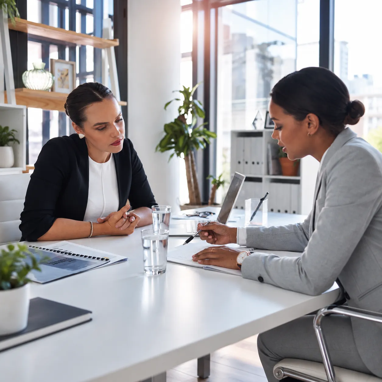 Two professionals review a candidate’s documents during an interview at an office desk.